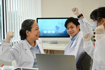 The Lab team working in the laboratory succeeds with their medical experiment, showing a happy and...