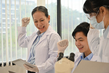 Happy team of research scientists success an important discovery While researching samples under the microscope