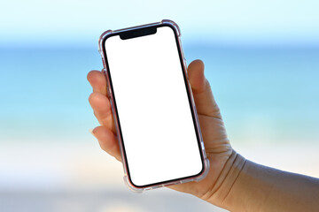 Elderly female Hand holding a smartphone on the beach, mobile mockup of a blank screen, Take screen...