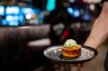 waiter hand hold dessert with ice cream and caramel
