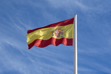 A Spanish Flag in Cartagena, Spain Blowing in the Wind with Blue Sky Background - 687107128