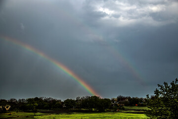 Double rainbow in the sky during rain in a cloudy sky over a village	
