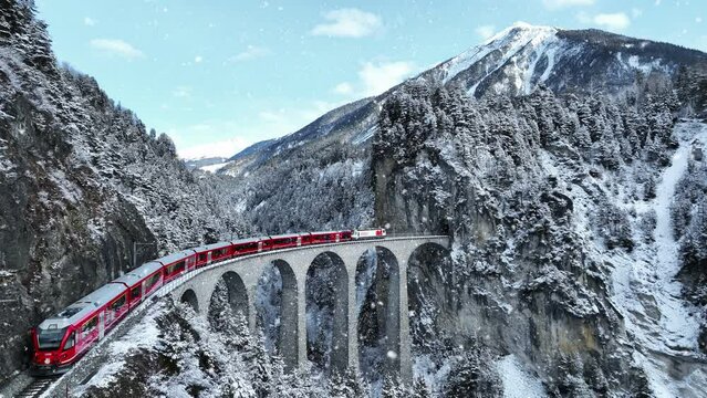 Snow falling and Train passing through famous mountain in Filisur, Switzerland. Train express in Swiss Alps snow winter scenery. 