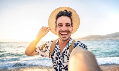 Deurstickers Happy handsome man taking selfie pic with cellphone outside - Male tourist enjoying summer vacation at beach holiday - Travel life style concept with smiling guy laughing at camera © Davide Angelini