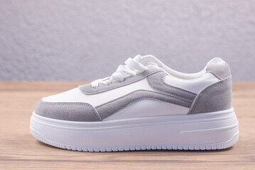 White sports sneakers on a wooden background. Footwear