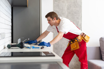 Young Repairman Installing Faucet Of Kitchen Sink In Kitchen Room