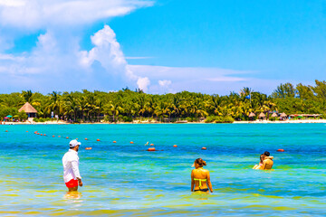 Tropical Caribbean beach people parasols fun Playa del Carmen Mexico.