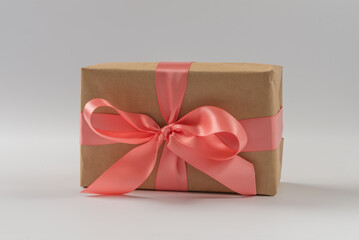 Brown paper gift box with silk rose ribbon on gray background