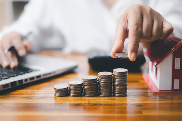 House model and money coins saving for concept saving money for buying a house, investment mortgage...