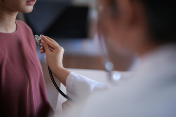 Asian psychologist women use stethoscope to examining heartbeat of patient and giving counseling...