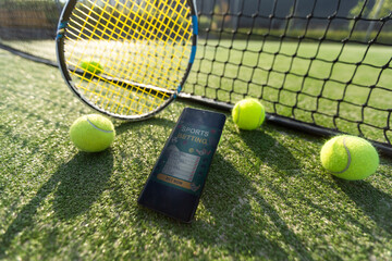 High angle view of mobile phone with tennis equipment on black background