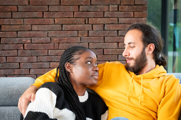 This image portrays a tender and intimate moment between two people, a mixed race couple. Seated...