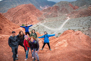 Grupo de turistas en la cumbre de un cerro colorado en Purmamarca, Argentina - obrazy, fototapety, plakaty