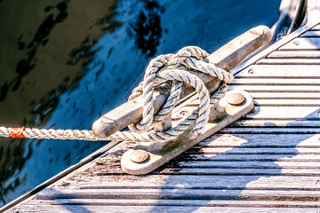 close up of yacht or boat mooring rope tied around cleat in harbour