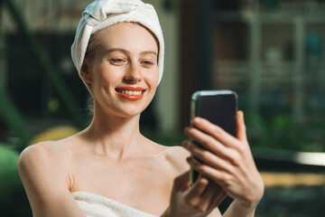 Portrait of close up beautiful caucasian woman in white towel taking video of calm and relaxing nature by using her mobile phone. Pretty girl with beautiful skin take photo. A Side view. Tranquility.