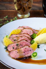 Roast duck fillet with mashed potato and orange sauce on wooden background