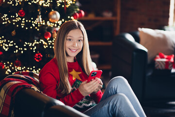 Photo of cheerful young teenager girl using smartphone browsing any new year gifts to buy for family on sales isolated indoors background