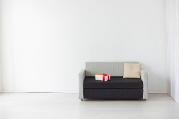 a sofa with a pillow and a gift in a bright room against a white wall