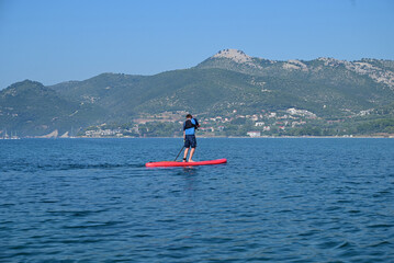 The serene activity of paddleboarding on the open sea, paddler navigating the open waters with a paddleboard, surrounded by the vast expanse of the sea.