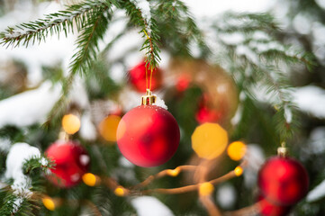 Red baubles on a snow-covered Christmas tree outdoors