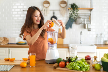 Portrait of beauty healthy asian woman making orange fruit smoothie with blender.girl preparing cooking detox cleanse with fresh orange juice in kitchen at home.health, vitamin c, diet, healthy drink