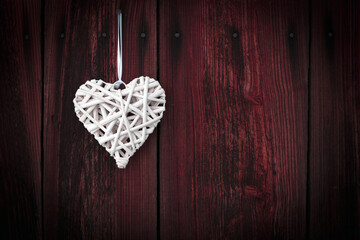 White wicker heart on wooden background