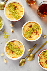 Baked rice pudding- traditional turkish milk dessert, served with pistachio nuts and cup of black tea. top view