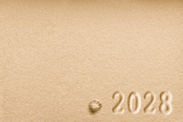 Fototapeta na wymiar Imprints of numbers 2028 new year and a shell left side on a golden sand