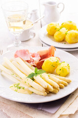 Traditional German white asparagus with boiled potatoes  and juniper ham served as close-up on a classic design plate