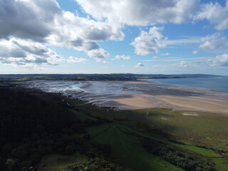 Fototapeta na wymiar Aerial photograph over the breathtaking fields by Red Wharf Bay in Anglesey, Wales, UK with village of Benllech in background at low tide
