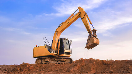Yellow excavator is leveling the ground for construction area of industrial building in construction site against blue sky background