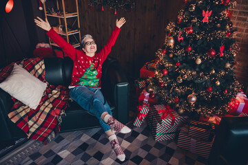 Full length photo of carefree grandmother sitting in divan raised palms up celebrating magic...