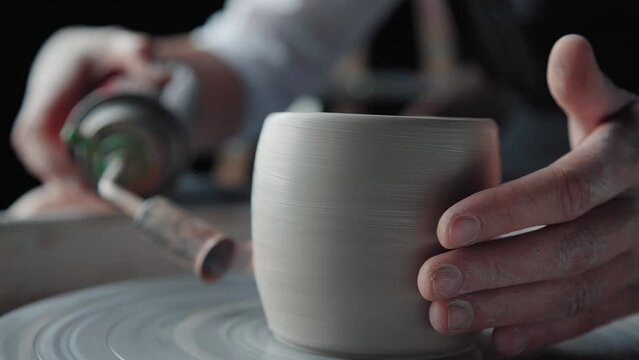 Potter works: firing clay on a potter's wheel. Close-up, only hands in the frame. Ceramist preform made of clay jars and makes roasting using the burner.