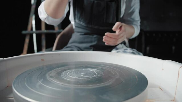 The potter puts a piece of clay on the potter's wheel and begins creative work. Woman ceramist working in workshop, medium shot, nature light