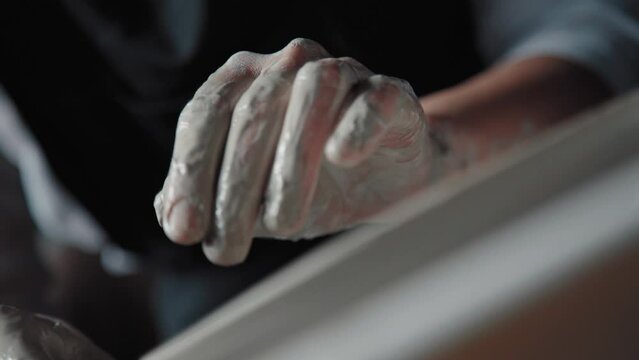 Clay plate on the potter's wheel, close-up. Potter with fingers and a sponge treats the edges of the clay product. Handicraft, pottery.