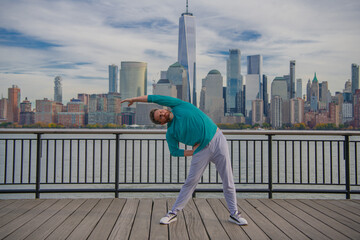 Man in fitness wear exercising near Manhattan. Healthy exercises. Active senior man is fitness exercising outdoor. Exercising after retirement. Mature retired sportsman doing stretching exercises.