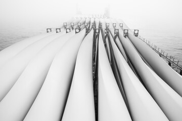Transportation of blades for wind turbines on a cargo ship across the ocean in fog. - obrazy, fototapety, plakaty