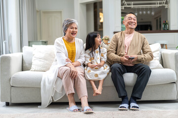 Portrait of happy love asian grandfather with grandmother and asian little cute girl enjoy relax at home.Young girl with their laughing grandparents smiling together.Family and togetherness