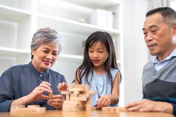 Portrait of happy love asian grandfather with grandmother and asian little cute girl enjoy relax at home.Young girl with their laughing grandparents smiling together.Family and togetherness