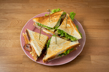 plate with Club sandwich on plate. above wooden table