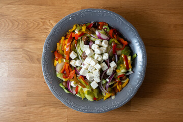 top view vegetable plate with feta cheese on top, on wooden table