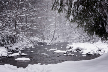 Krajobraz zimowy, górska rzeka, wodospad i zaśnieżone drzewa