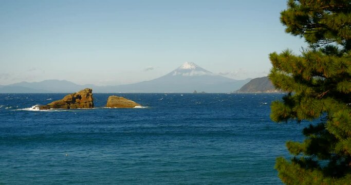 富士山と二つに割れた岩が観える海の風景。