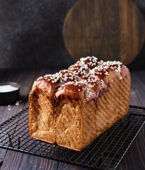 Butter brioche bread sprinkled with pearl sugar on black grille on a dark wooden background.  Wheat bread recipes.