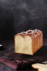Butter brioche bread sprinkled with pearl sugar on black grille on a dark wooden background.  Wheat bread recipes.