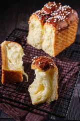 Butter brioche bread sprinkled with pearl sugar on black grille on a dark wooden background.  Wheat bread recipes.