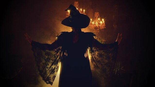 Fantasy woman witch back rear view walks creates magic hands raised spell ritual in dark gothic room full smoke candles burning sexy girl Black dress Pointed Hat. performance show party Art video 4k