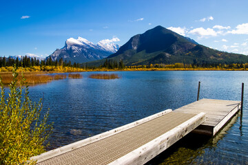 A wooden dock in Vermillion Lake with Rundle mountain in the background.