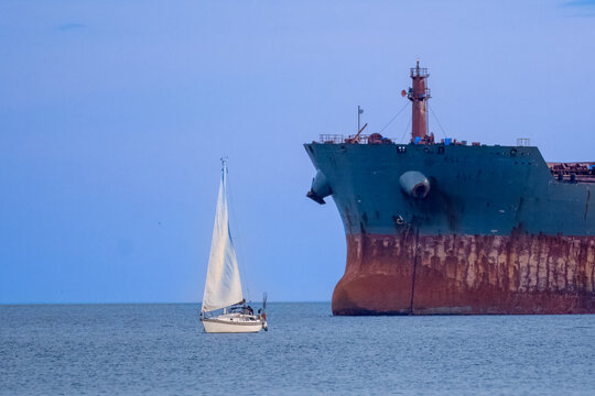 Sailboat sailing past a tanker in ocean, Victoria, British Columbia, Canada