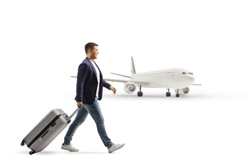 Full length profile shot of a man pulling a suitcase in front of a plane